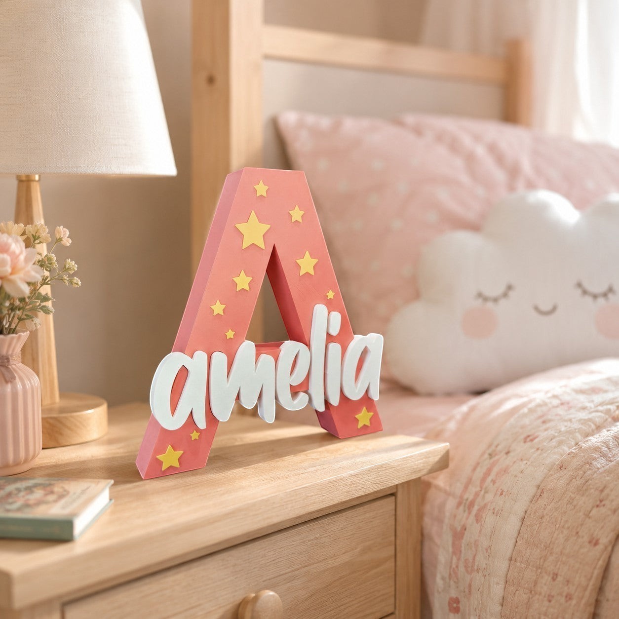 Stone Look Statues personalized pink letter A with yellow stars and white name Amelia on a wooden nursery nightstand.