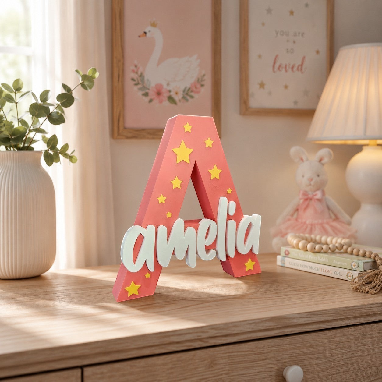 Stone Look Statues pink letter A nursery decor with yellow stars and white Amelia name cutout on a wooden dresser.